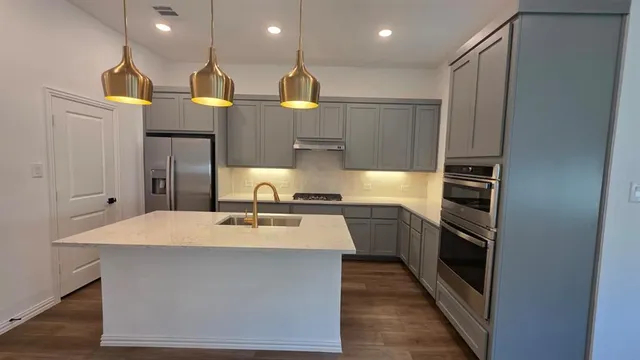 a kitchen with kitchen island wooden cabinets and refrigerator