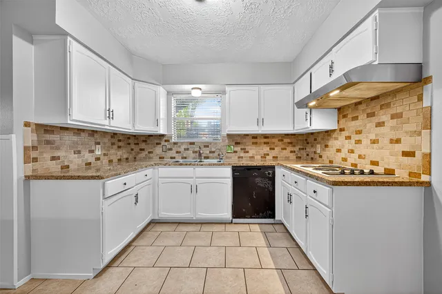 a kitchen with granite countertop a sink a stove and cabinets