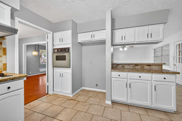 a kitchen with white cabinets and refrigerator