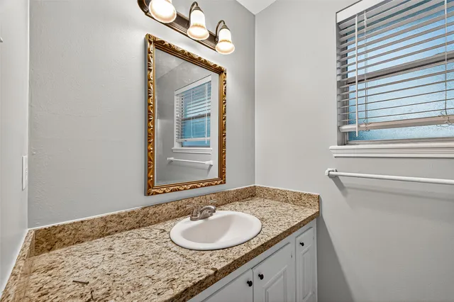 a bathroom with a granite countertop sink and a mirror