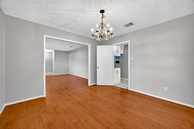 a view of a big room with wooden floor and chandelier