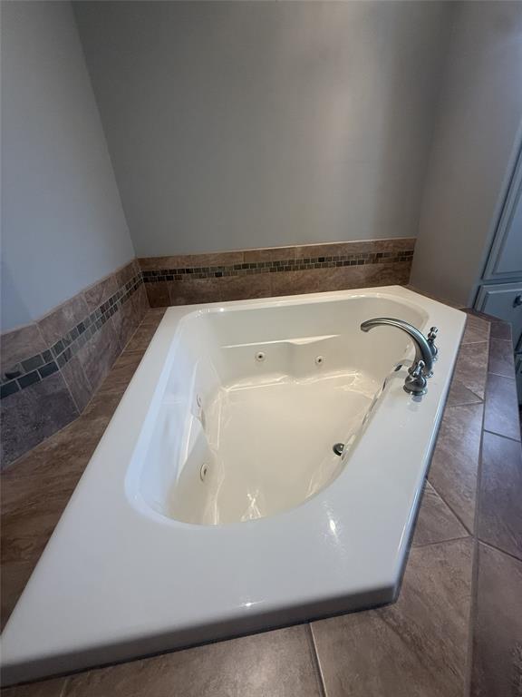 304 6th Street Northwest Springhill, LA 71075 - Photo 10 of 38 Integrated jetted bathtub with a deck-mounted faucet, surrounded by tiled flooring and a tiled wall border