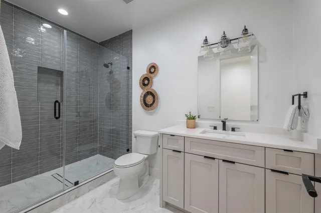 a bathroom with a toilet a sink a mirror and shower