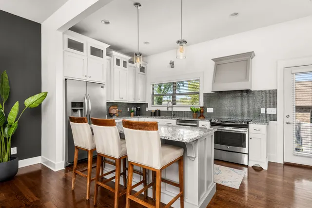 a kitchen with stainless steel appliances granite countertop a stove top oven a refrigerator a sink and a dining table with wooden floor