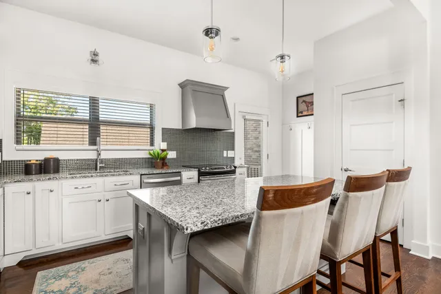 a kitchen island with granite countertop a sink stove and cabinets