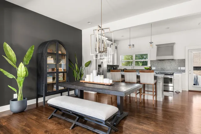 a kitchen with stainless steel appliances a dining table chairs and couches with wooden floor