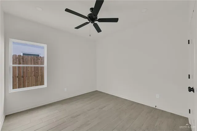 an empty room with a window and a ceiling fan