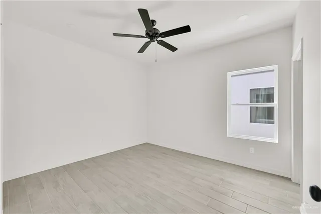 an empty room with a ceiling fan and windows