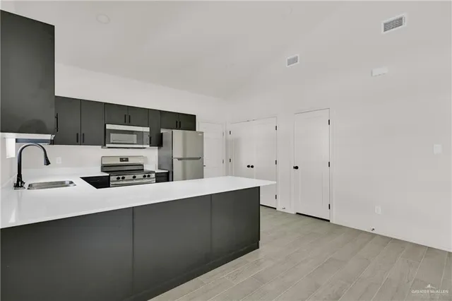 a kitchen with stainless steel appliances a sink a stove a microwave a sink a refrigerator and cabinets