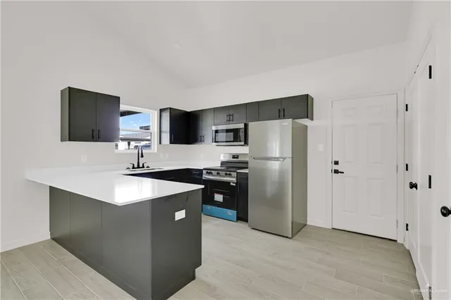 a kitchen with stainless steel appliances granite countertop a refrigerator a sink a stove a microwave and a refrigerator