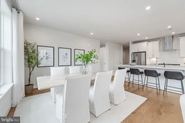 a living room with furniture a dining table and kitchen view with wooden floor