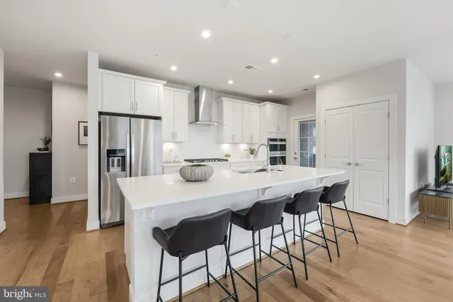 a kitchen with stainless steel appliances a dining table chairs and wooden floor