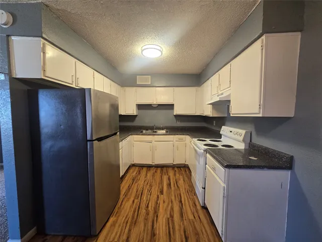 a kitchen with a refrigerator a sink and wooden cabinets