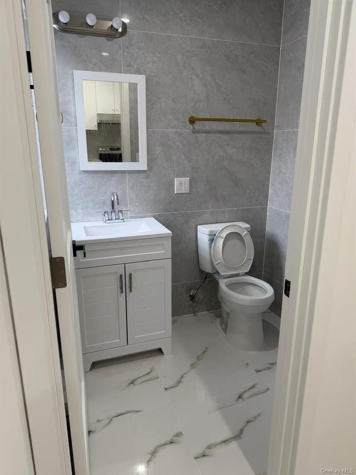 86-05 Britton Avenue, Unit 2 Queens, NY 11373 - Photo 4 of 7 a bathroom with a toilet sink and mirror