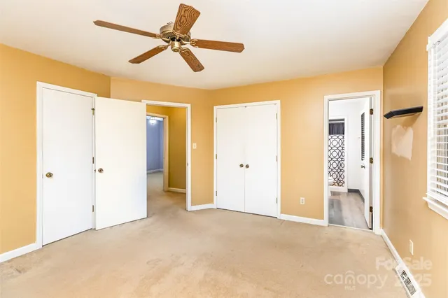 a view of a livingroom with a chandelier fan and windows
