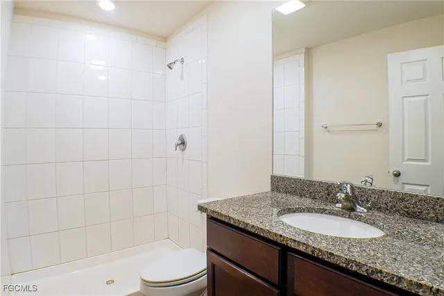 a bathroom with a granite countertop sink toilet a mirror and shower