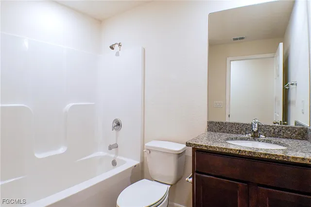 a bathroom with a granite countertop sink toilet a large mirror a bathtub and shower