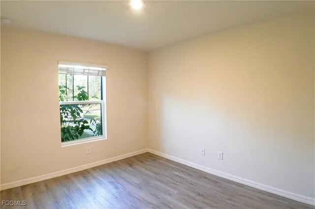 an empty room with wooden floor and window