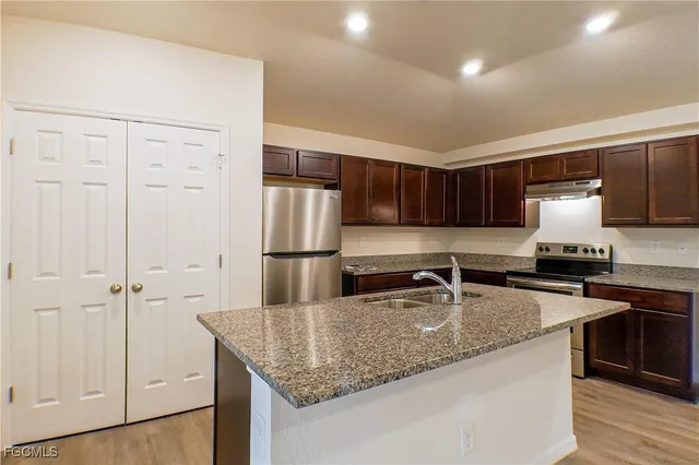 a kitchen with kitchen island granite countertop a sink stove and refrigerator
