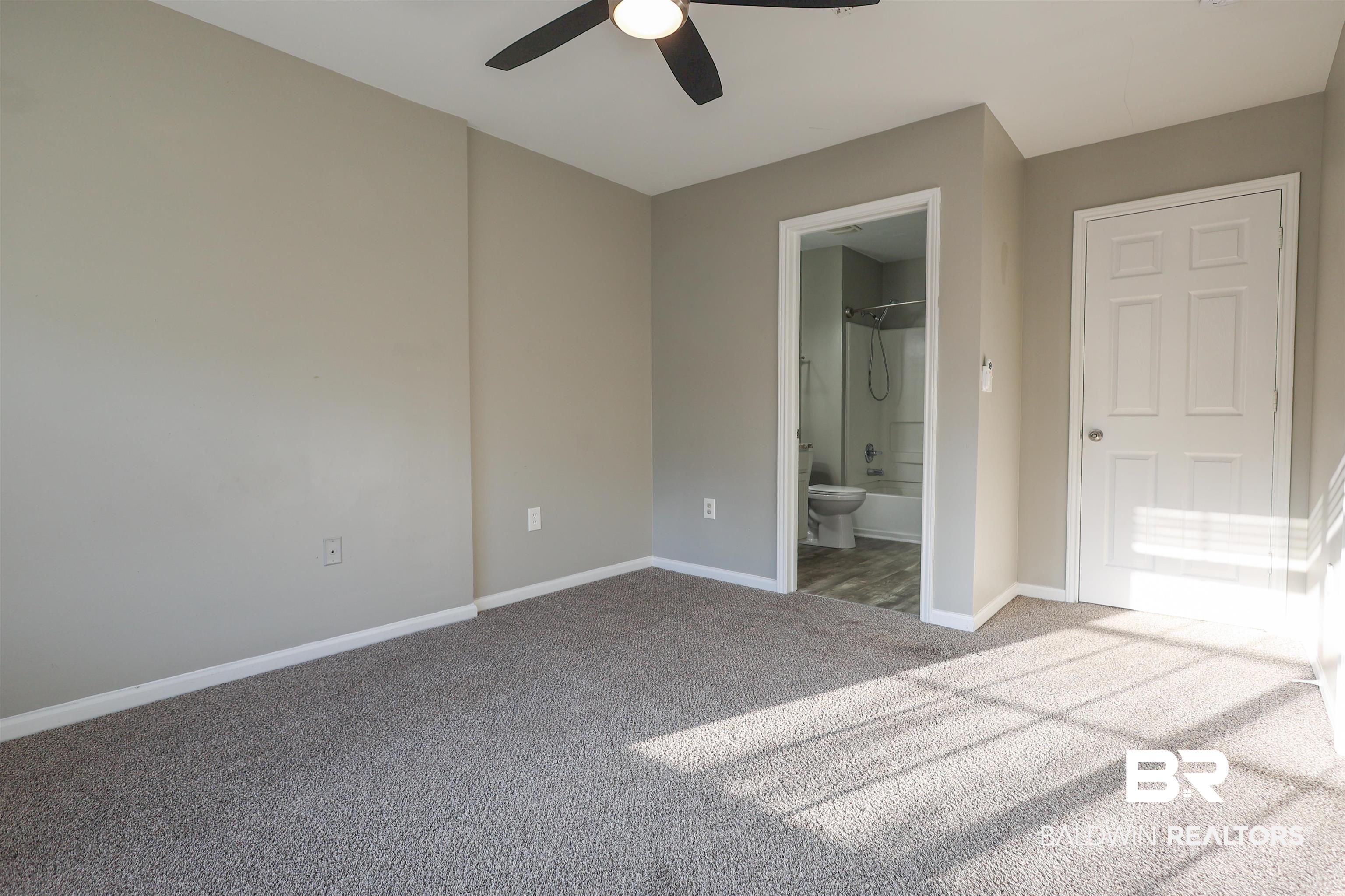 1517 Regency Road, Unit 125 Gulf Shores, AL 36542 - Photo 13 of 26 Unfurnished bedroom with ensuite bathroom, carpet flooring, and ceiling fan