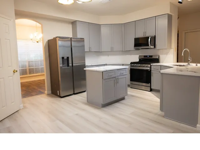 a kitchen with stainless steel appliances kitchen island granite countertop a refrigerator stove and microwave