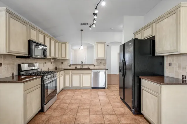 a kitchen with stainless steel appliances granite countertop a refrigerator a stove top oven a sink and dishwasher