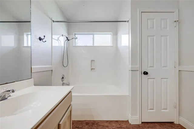 a bathroom with a tub shower vanity and a sink