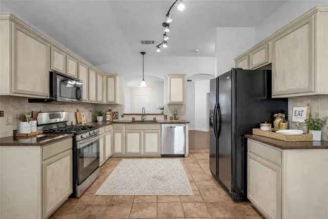 a kitchen with stainless steel appliances granite countertop a refrigerator stove a sink and dishwasher with white cabinets