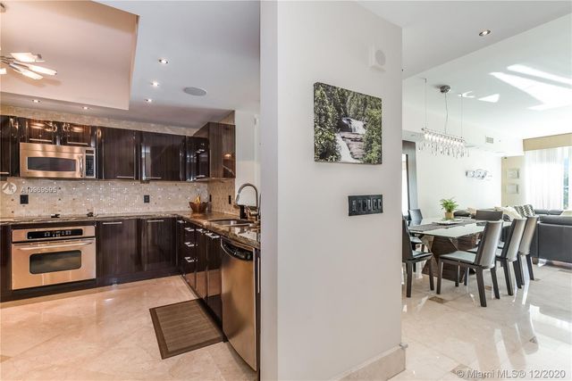 a kitchen with stainless steel appliances granite countertop a stove top oven a sink a dining table and chairs