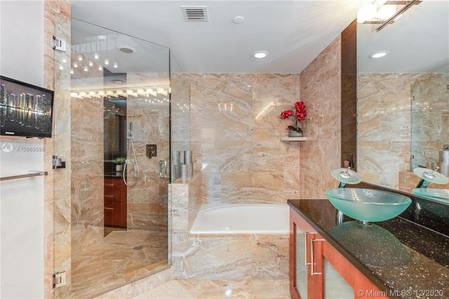 a bathroom with a granite countertop shower a sink and a mirror