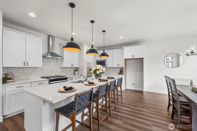 a kitchen with stainless steel appliances granite countertop a stove a kitchen island a dining table and chairs with wooden floor