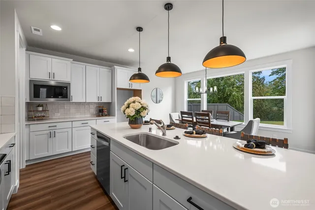 a kitchen with stainless steel appliances granite countertop a sink a stove and a wooden floors