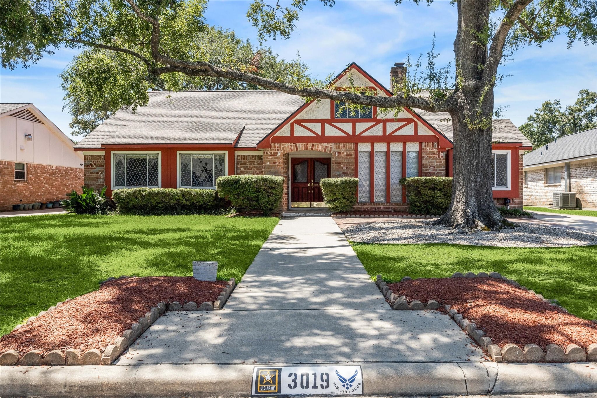 3019 Stetson Lane Houston, TX 77043 - Photo 2 of 28 Classic Tudor design featuring diamond-pane windows, bold red trim, and a spacious front yard with a shaded walkway.