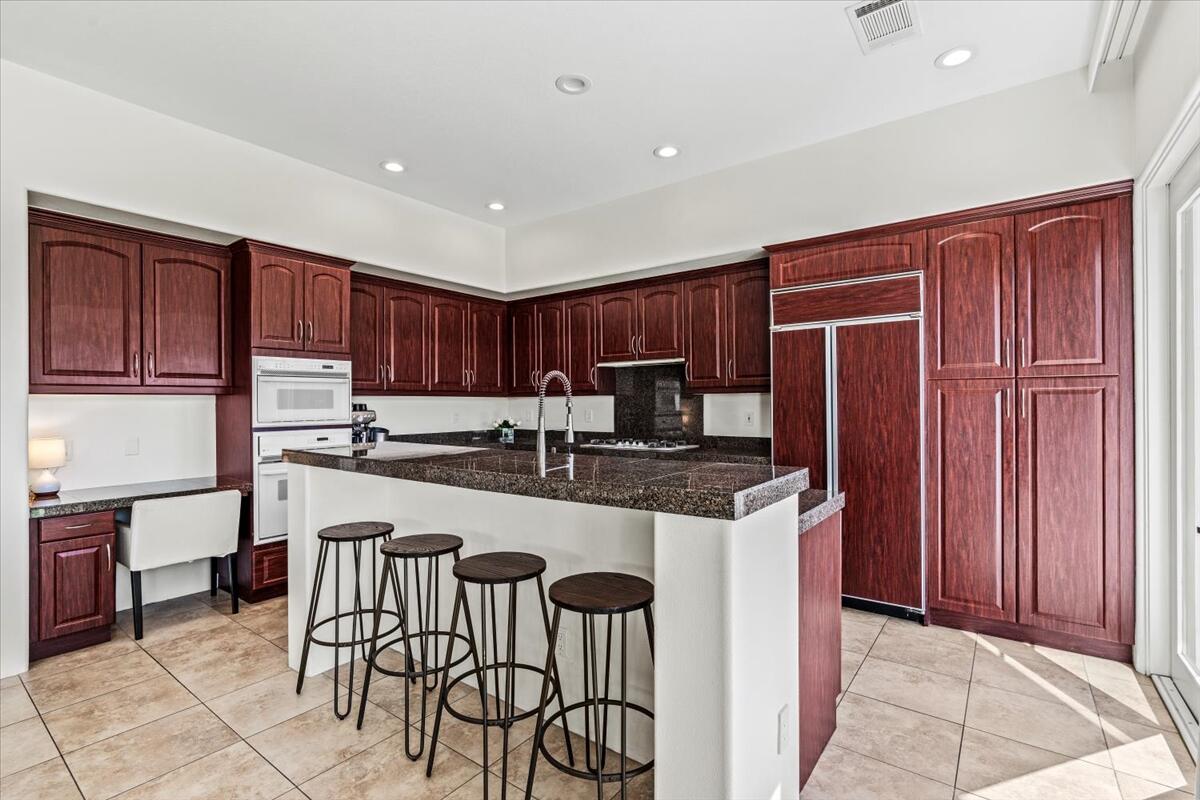 54695 Winged Foot La Quinta, CA 92253 - Photo 19 of 51 a kitchen with stainless steel appliances granite countertop a table chairs sink and cabinets