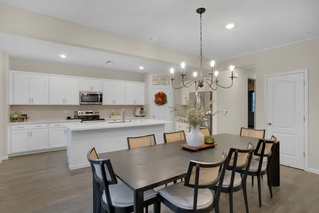 a kitchen with stainless steel appliances kitchen island granite countertop a dining table chairs and white cabinets