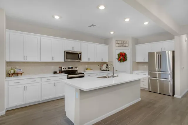 a kitchen with a sink stainless steel appliances and white cabinets