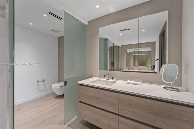 a bathroom with a toilet a double vanity sink and mirror