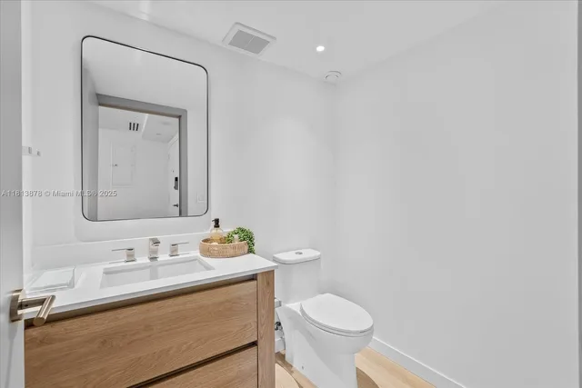 a bathroom with a granite countertop sink toilet and mirror