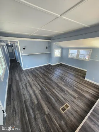 a view of empty room with stairs and wooden floor