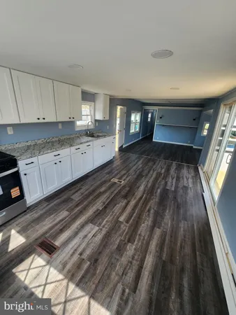 a view of a kitchen with kitchen island a sink wooden floor and stainless steel appliances