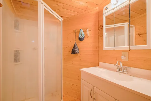 a bathroom with a granite countertop sink a mirror and shower