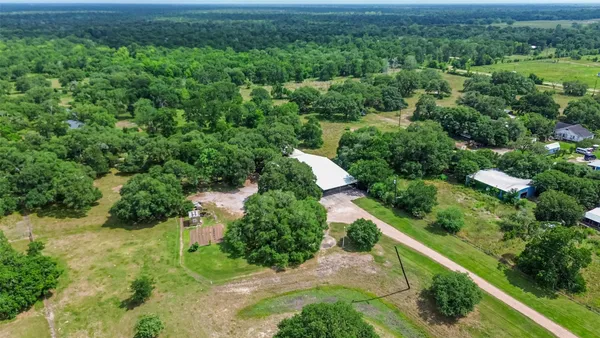 an aerial view of residential house with outdoor space and trees all around