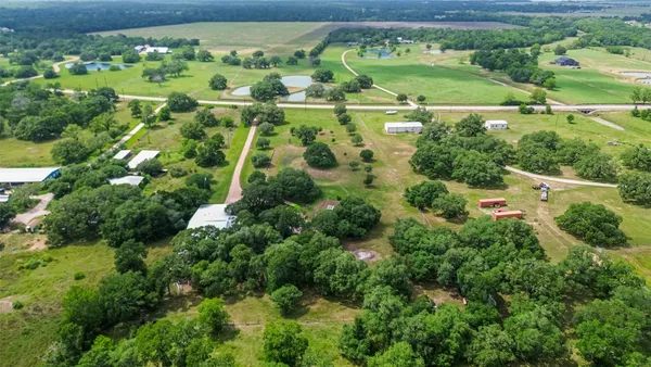 an aerial view of residential house with outdoor space and trees all around