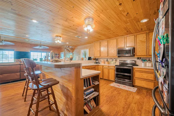 a kitchen with stainless steel appliances kitchen island granite countertop a table chairs and a refrigerator