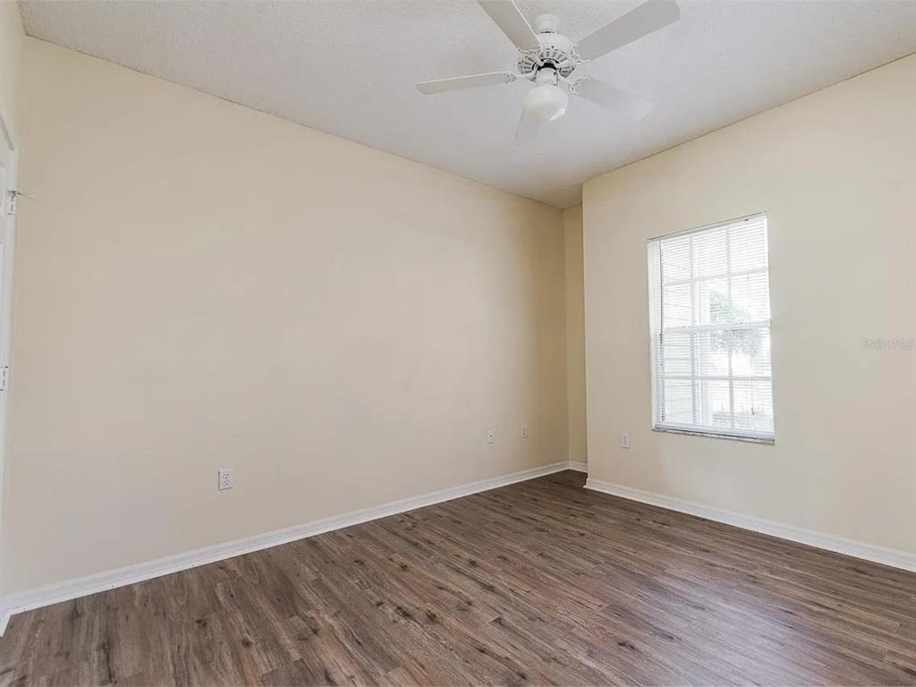 10000 Southwest 52nd Avenue, Unit 99 Gainesville, FL 32608 - Photo 12 of 19 an empty room with wooden floor fan and windows