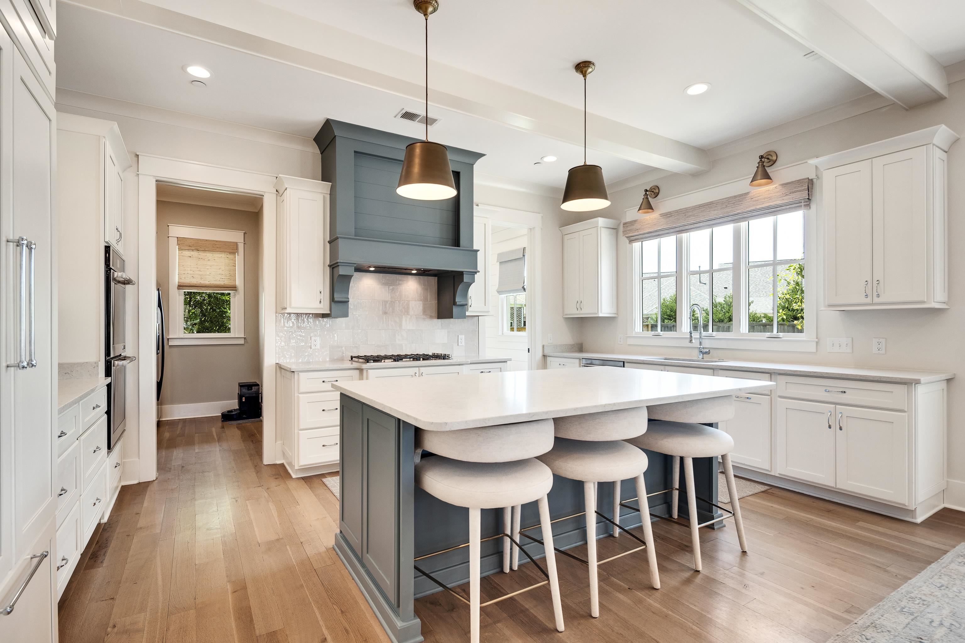100 Sunflower View Road Piperton, TN 38017 - Photo 10 of 29 Gourmet kitchen featuring a substantial island with countertop seating, white shaker cabinetry, light wood-finish flooring, a blue-toned range hood, and double wall ovens