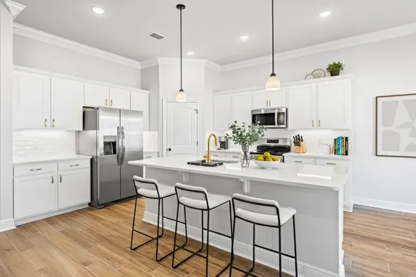 a kitchen with stainless steel appliances granite countertop a sink a stove a refrigerator and island with wooden floor