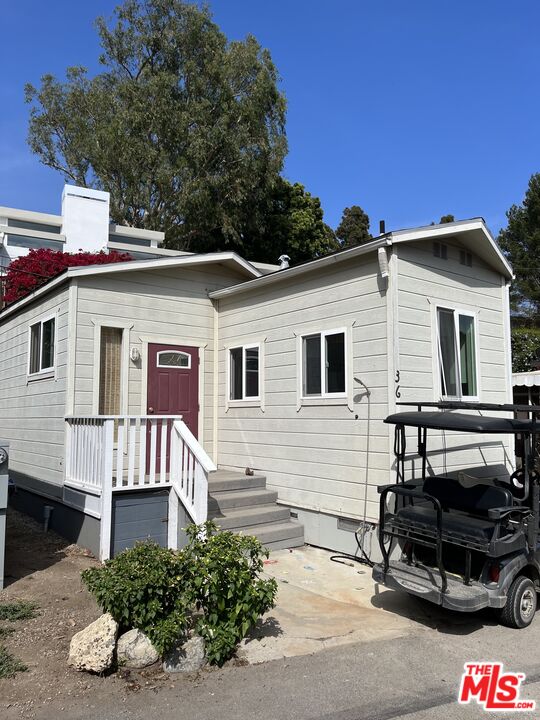 a view of a white house with a yard and potted plants