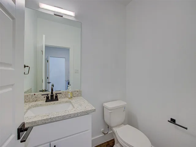 a bathroom with a granite countertop toilet sink and mirror
