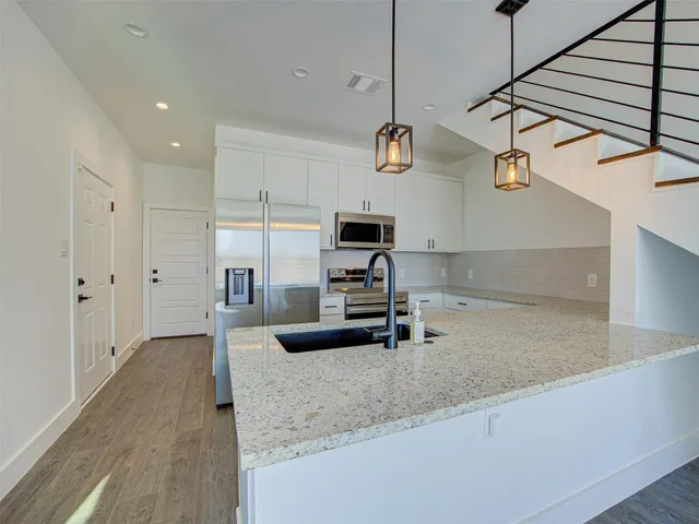 a kitchen with stainless steel appliances granite countertop a sink a stove and a wooden floors